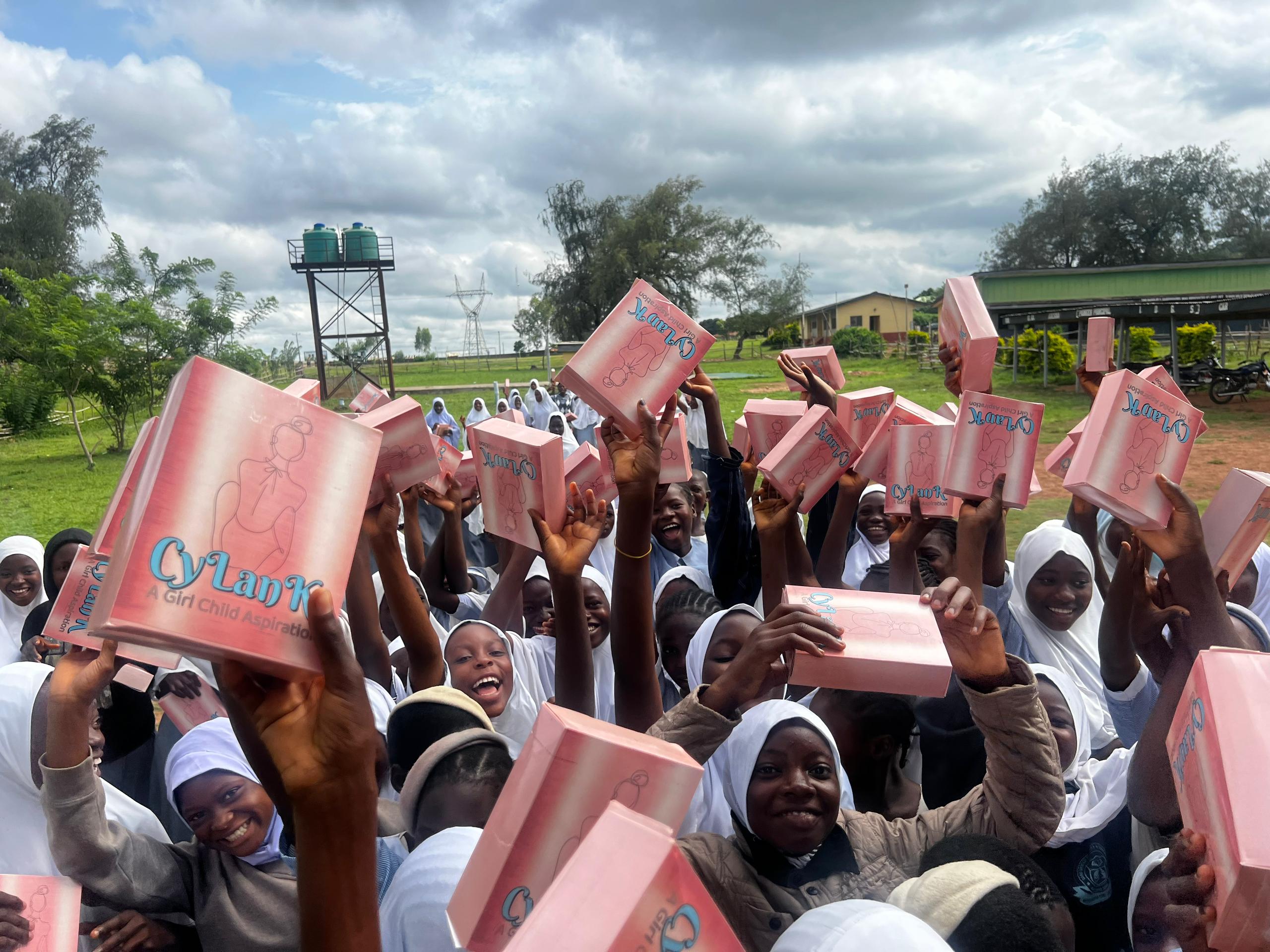 Students celebrating with CyLanK pad boxes at outdoor distribution